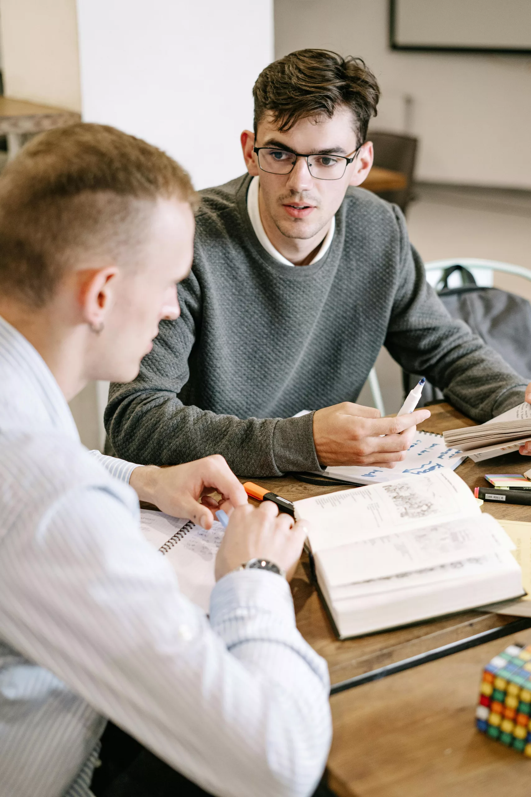 Two young men studying together at a table with books and notes.
