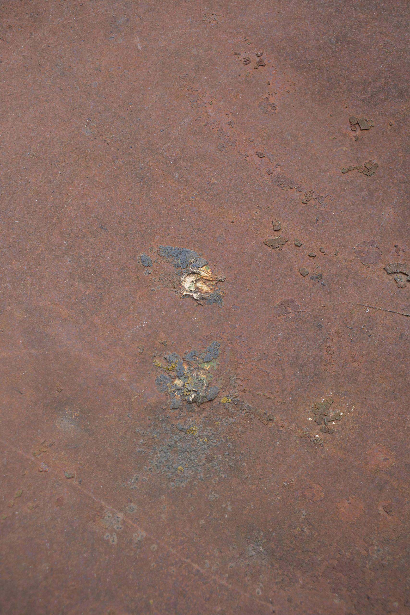 Close-up of a textured, weathered metal surface showing rust and decay.