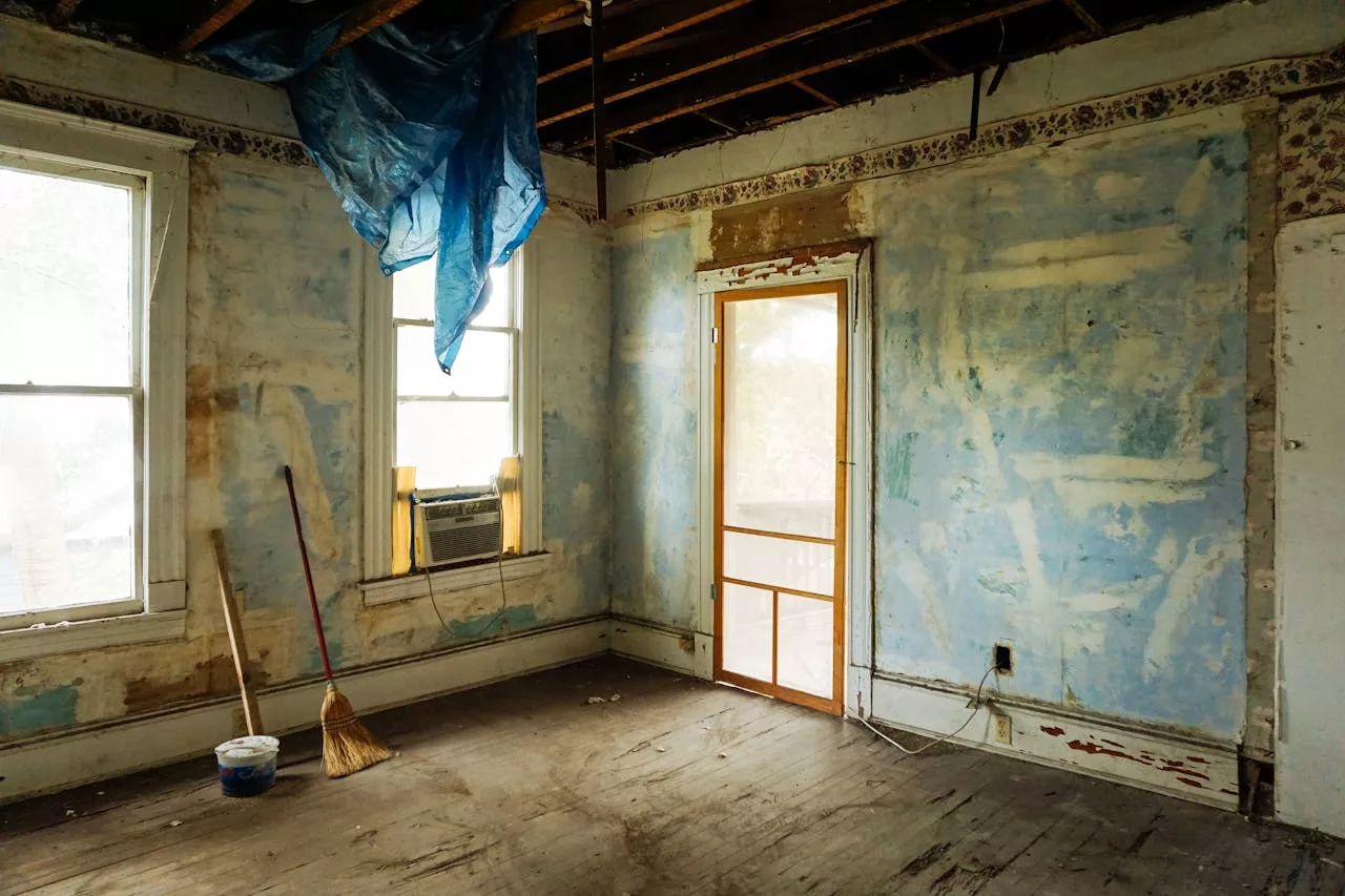 services-02 An empty room in an abandoned house with peeling walls and construction tools.