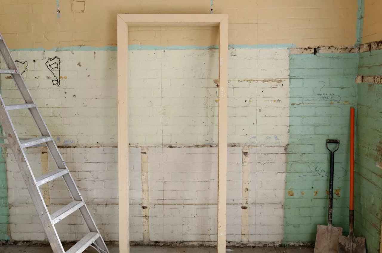services-01 Renovation scene featuring ladder, frame, and tools against partially demolished walls.